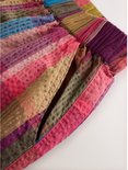 Detail van een geruite broek met wijde pijpen in rood, paars, groen en bruin.