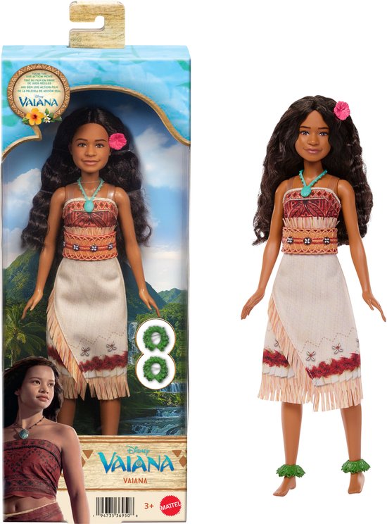 Vaiana pop in verpakking, met lange bruine krullen, turquoise ketting, traditionele outfit en groene enkelbanden. Naast de pop staat de verpakking.