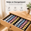 Zwarte lade organizer met 24 vakken, gevuld met gevouwen sokken in wit, blauw, roze en geel.