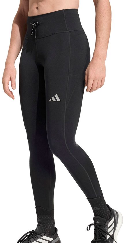 Model in zwarte Adidas legging met drievoudige streep logo op de linker heup.