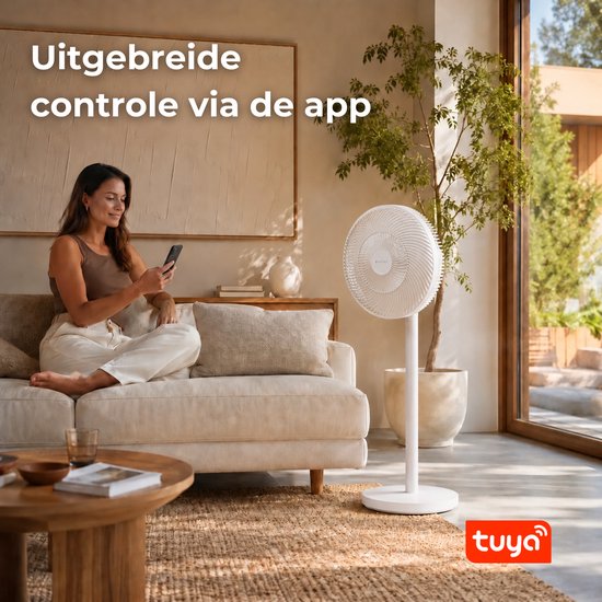 Een vrouw zit op een bank en bedient een witte staande ventilator met haar smartphone. "Uitgebreide controle via de app" staat in tekst op de afbeelding.