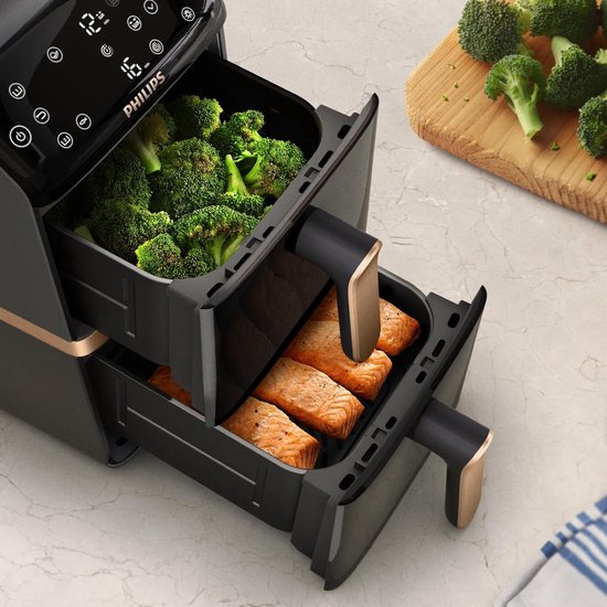 Zwarte Philips Airfryer met gouden handvatten. Bovenste lade met broccoli, onderste lade met zalm.