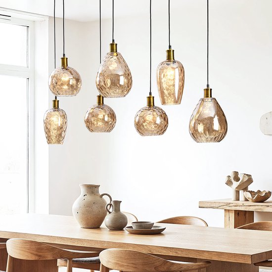 Suspensions avec abat-jours en verre ambré au-dessus d'une table à manger en bois.