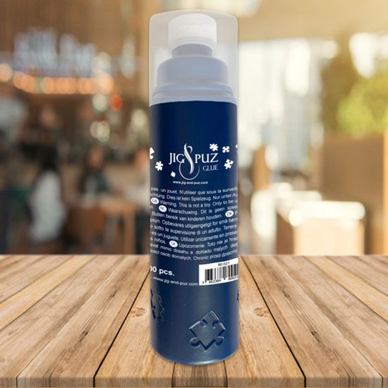 Fles met puzzellijm, met sponsapplicator. Met de tekst 'JIG & PUZ GLUE', op een houten tafel.