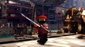 Een rood met zwarte Lego-ninja met masker en zwaard in een stedelijke omgeving met gebouwen en water.