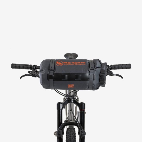 Grijze fietstas met oranje logo, bevestigd aan het stuur van een mountainbike.