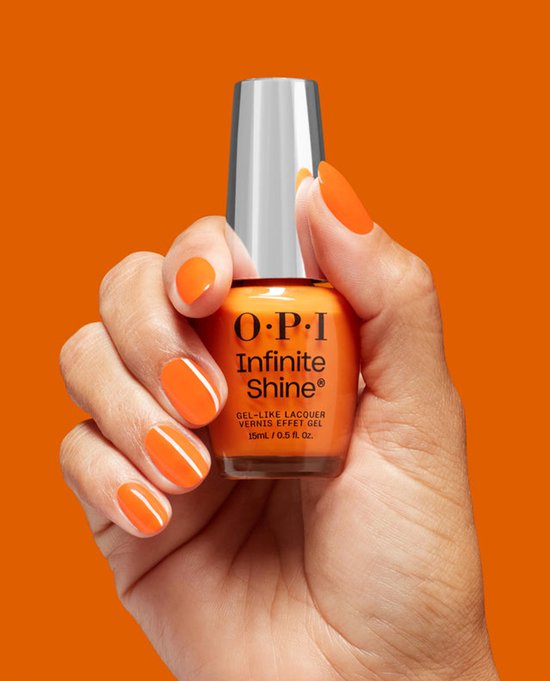 Hand met glanzend oranje gelakte nagels die een flesje O.P.I. Infinite Shine nagellak vasthoudt.