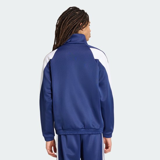Zijaanzicht van de achterkant van een donkerblauwe sportjack met witte schouderaccenten en Adidas logo.