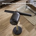Bladloze ventilator met magnetische afstandsbediening op de vloer naast een salontafel.