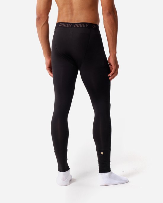 Dos d'un homme portant un legging long thermique noir avec des chaussettes blanches.