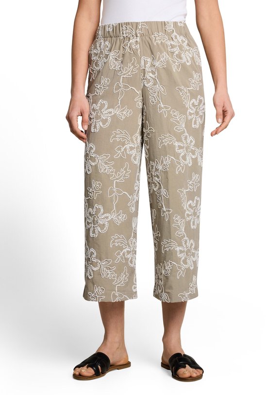 Vrouw in lichtbruine culotte met witte bloemenborduring en elastische tailleband.