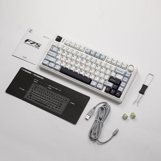 Wit mechanisch toetsenbord met accessoires, waaronder een handleiding, polssteun en USB-kabel.