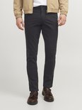 Man in zwarte chino broek met bruine loafers en een beige bomberjack.