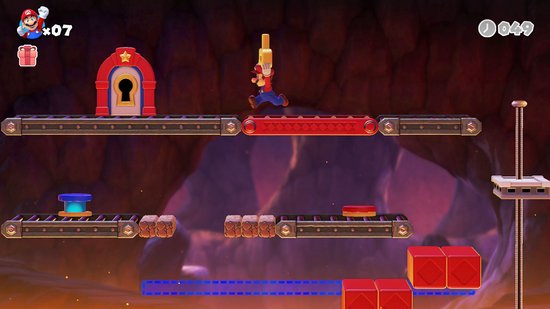 Mario rent op een platform in een grot. Hij springt over een vuurkuil met een sleutel op een lopende band.