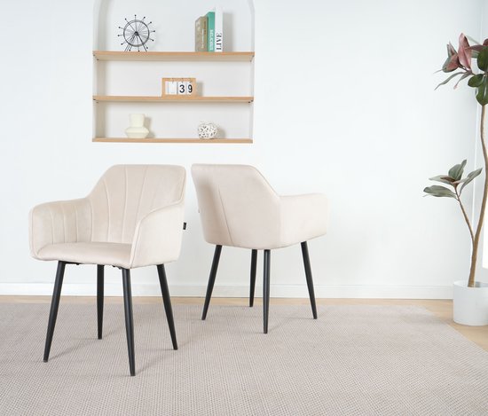 Twee crème fluwelen eetkamerstoelen met zwarte poten, geplaatst op een lichtgrijs tapijt.