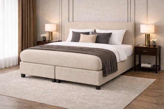 Boxspringbed in beige stof met twee lades en gestoffeerd hoofdbord. Gedecoreerd met bruine en grijze kussens.