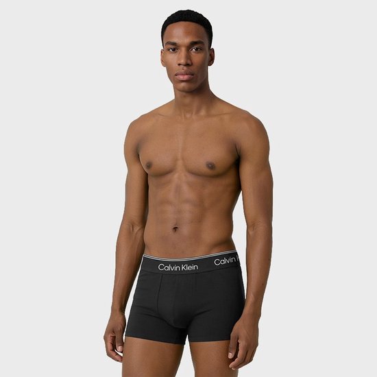 Man met zwarte Calvin Klein trunks. Opdruk op de tailleband.