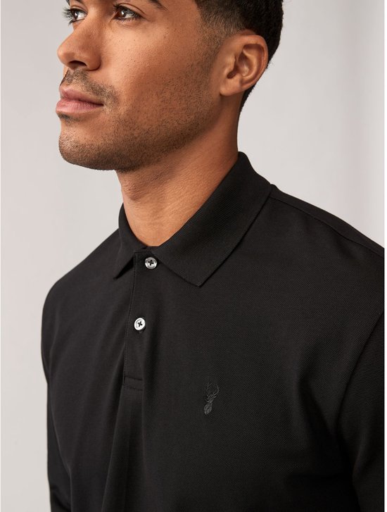 Close-up van een zwart poloshirt met lange mouwen, met geborduurd hertje en knopen.