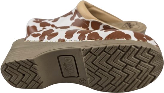 Zool van een witte klomp met bruine koeienvlekkenprint. Beige zool met 'DINA CLOGS' logo en maat 37.