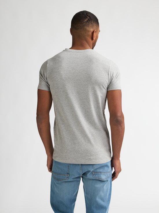 Man, achterkant van een effen lichtgrijs T-shirt met korte mouwen en een lichtblauwe jeans.
