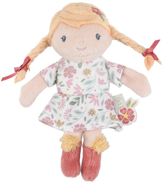 Een zacht speelgoedpopje met blonde vlechten, een wit jurkje met bloemenprint en roze laarsjes met bontrandje, zittend.