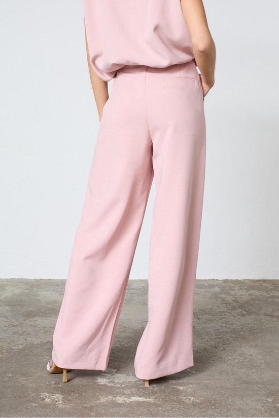 Achterkant van een lichtroze wijde broek, gedragen met een bijpassend mouwloos topje.