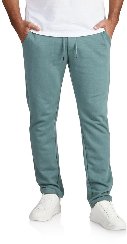 Man in een donkergroene joggingbroek met trekkoord, witte sneakers en een wit T-shirt.