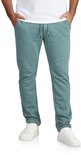 Man in een donkergroene joggingbroek met trekkoord, witte sneakers en een wit T-shirt.