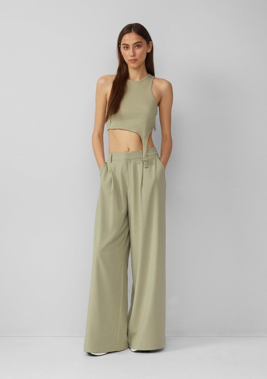 Model draagt een lichtgroene, wijde broek met hoge taille en een bijpassend crop top met cut-outs.