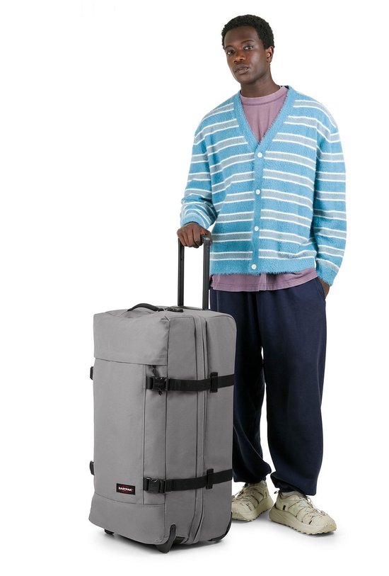 Man naast een grote grijze Eastpak koffer met zwarte details en wielen.
