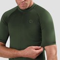 Man die de mouw van een donkergroen wielershirt aanpast. Het shirt heeft een textuur.