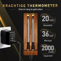 Twee zilverkleurige vleesthermometers in een houten kistje, opgeladen via een witte adapter.