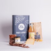 Een cadeaupakket met kaas, worst, worstbroodjes, appelsap, chips en noten.