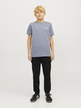Jongen in grijze t-shirt en zwarte cargobroek, staand.
