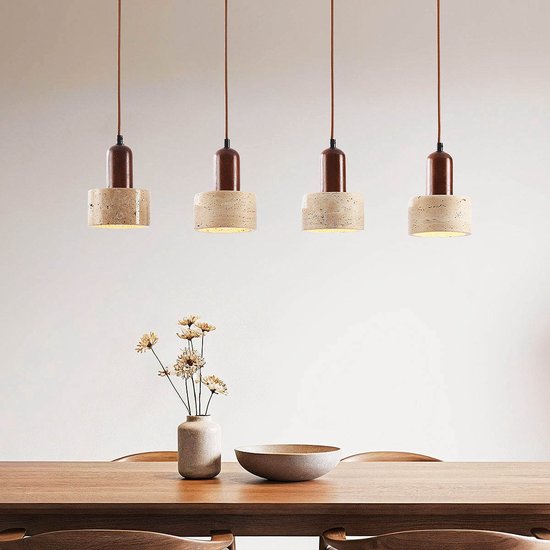 Quatre suspensions au-dessus d'une table à manger avec vase et bol. Les lampes ont des abat-jours en travertin et des détails marron.