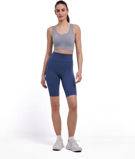 Model van voren gezien in blauwe, nauwsluitende capri-legging met textuur en een grijze sportbeha.