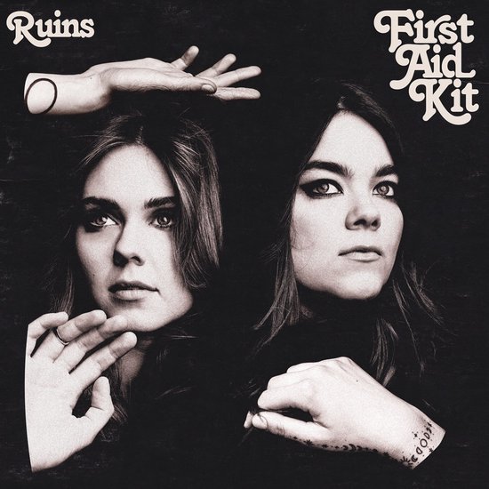 Twee jonge vrouwen, de een met haar hand op haar kin en de ander met haar hand boven haar hoofd, tegen een zwarte achtergrond. "First Aid Kit Ruins"