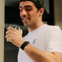 Man in witte t-shirt drinkt een glas sinaasappelsap met een groene activity tracker om de pols.