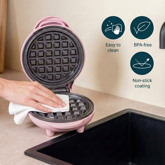 Roze wafelijzer open, met hand die het schoonmaakt. Iconen voor makkelijk schoonmaken, BPA-vrij, anti-aanbaklaag.