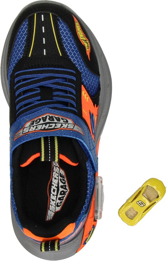 Zicht op de bovenkant van een zwarte sneaker met blauwe en oranje details, en een kleine gele speelgoedauto.