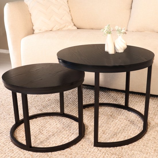 Set van twee ronde bijzettafels in het zwart, met een vaasje met bloemen op de grootste tafel.
