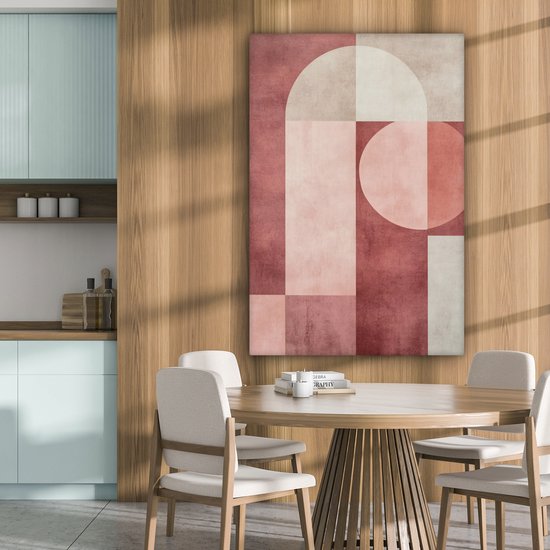 Peinture abstraite rose, beige et blanc avec des formes géométriques accrochée au-dessus d'une table de salle à manger ronde dans une cuisine.