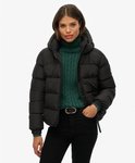 Zwarte pufferjas met capuchon, gedragen door een model met groene coltrui.