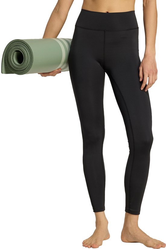 Onderlichaam van een vrouw in zwarte legging, met groene yogamat.