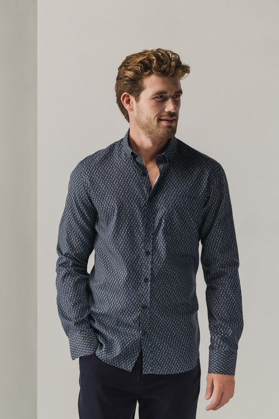 Model met donkerblauw overhemd met geometrische print en knoopsluiting.