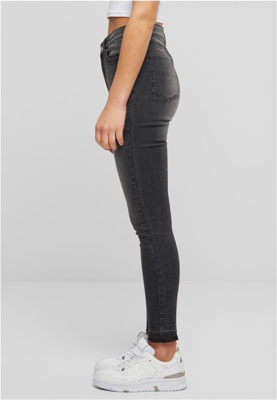 Zij-aanzicht van een dames skinny jeans in zwart gewassen denim met rafelige zoom.