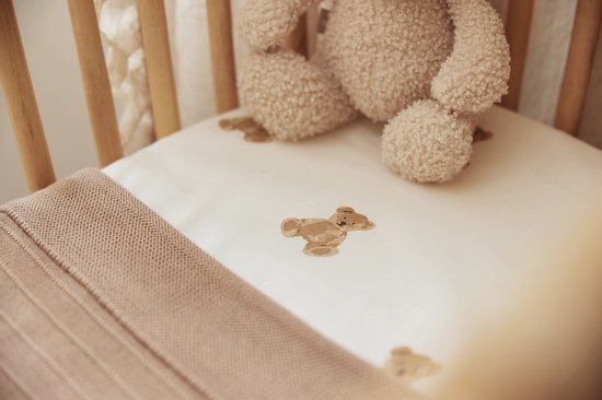 Drap de lit crème à imprimé ours en peluche, avec une couverture tricotée beige.