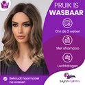 Model draagt een golvende, half-lange, donkerblonde pruik. Tekst: 'Pruik is wasbaar', met iconen voor wassen en luchtdrogen.