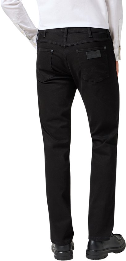Man van achteren gezien, met een zwarte Wrangler jeans met rechte pijpen.