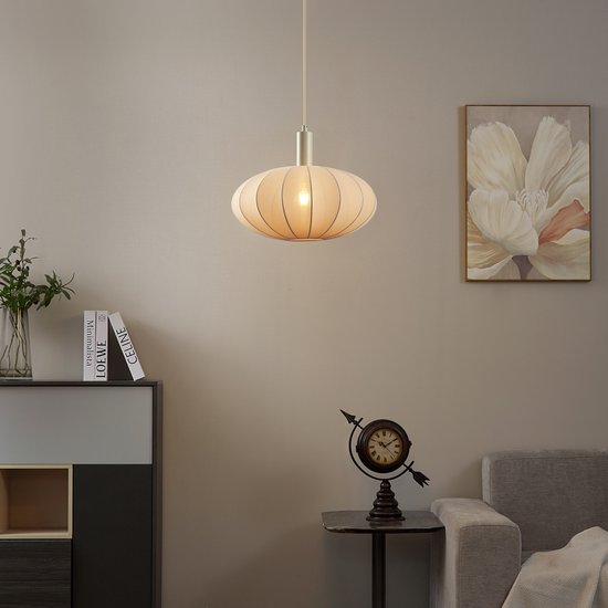 Beige hanglamp met stoffen kap in een woonkamer, boven een dressoir en naast een fauteuil.